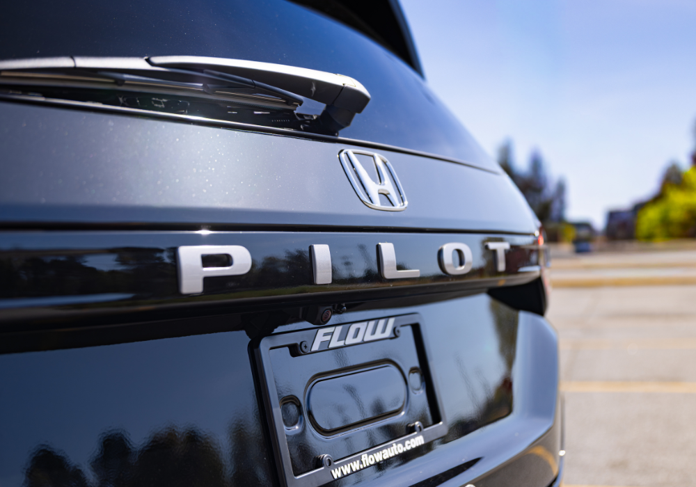 Rear exterior view of the new Honda Pilot. The SUV is blue and it is parked on a gravel road. 