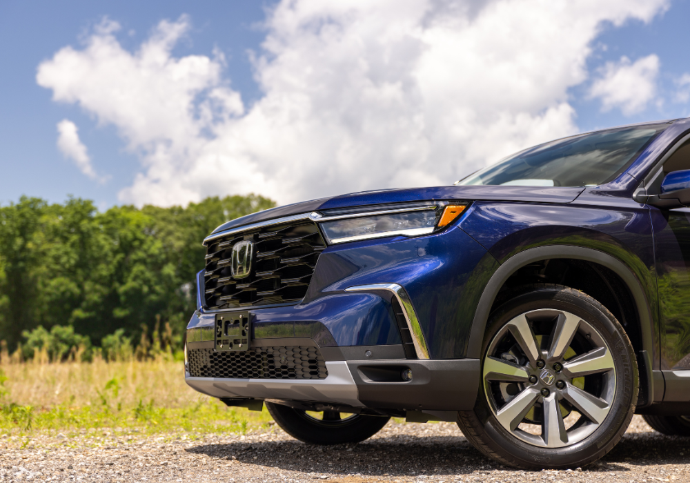 Close up photo of the front half of a new 2025 Honda Pilot. The Honda logo is visible on the front grille.